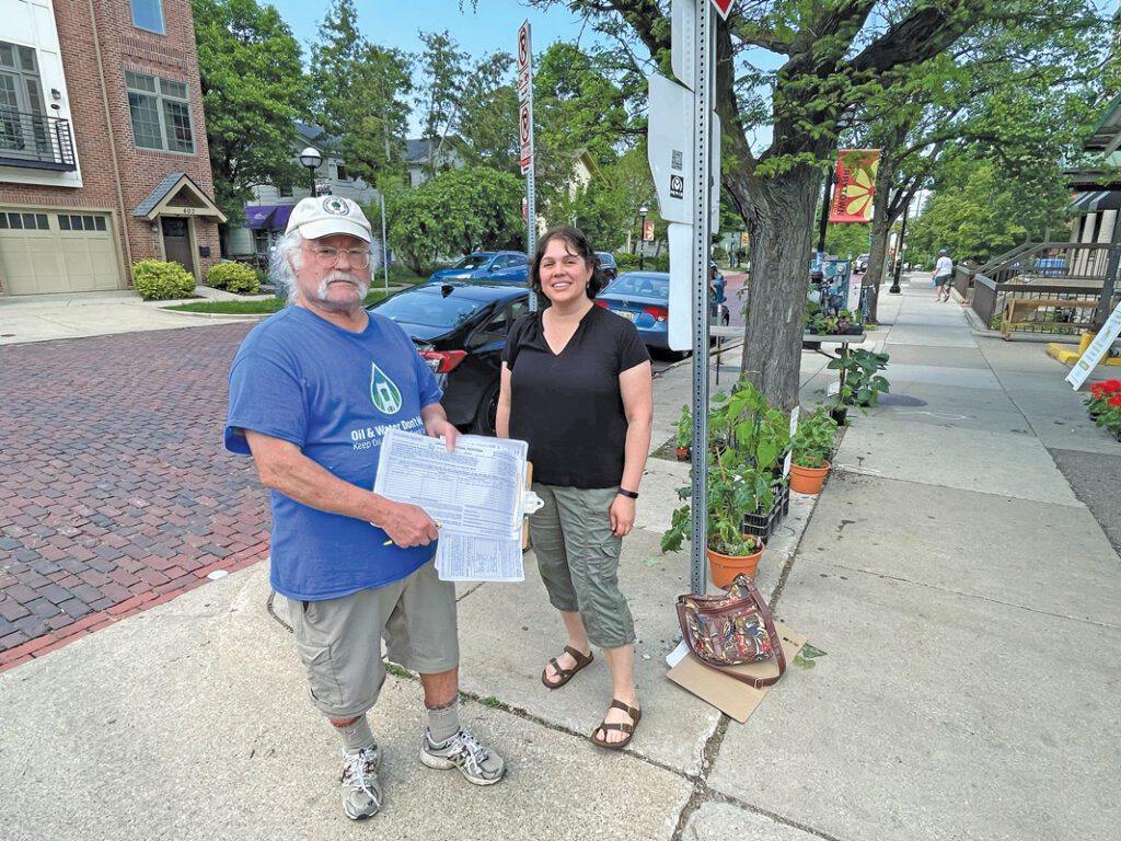 Ed Steinman holds a petition next to Kristie Shaffer outside the Ann Arbor Farmers Market.