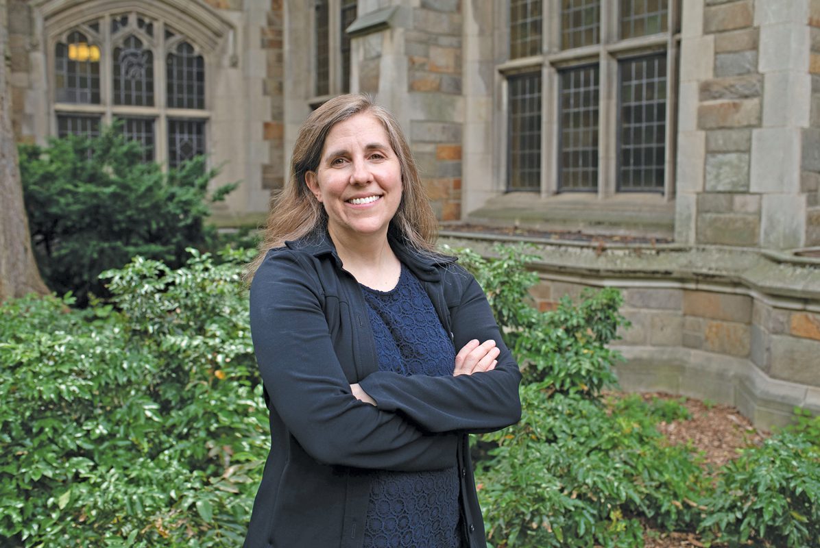 A woman standing in front of a building with her arms crossed. 