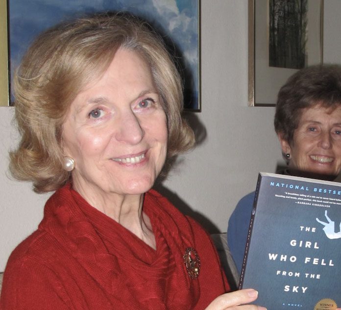 A smiling woman holding a book. 