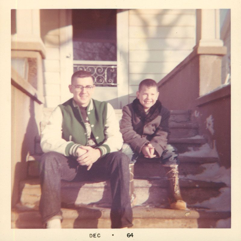 Old photo of two boys sitting on stairs. 