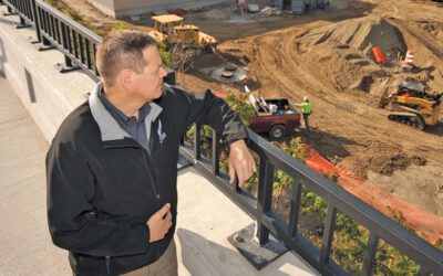 A man standing on a bridge looking down at construction.