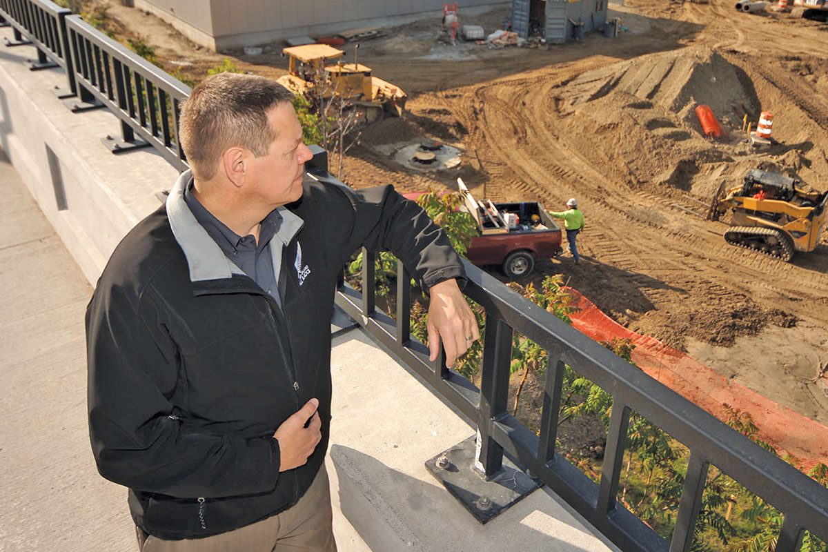 A man standing on a bridge looking down at construction.