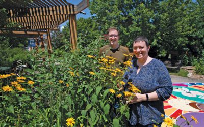 A man and woman standing near some flowers.