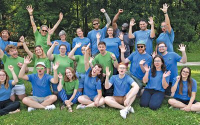 A group of people gesturing enthusiastically in a park.