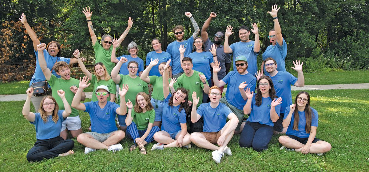 A group of people gesturing enthusiastically in a park.