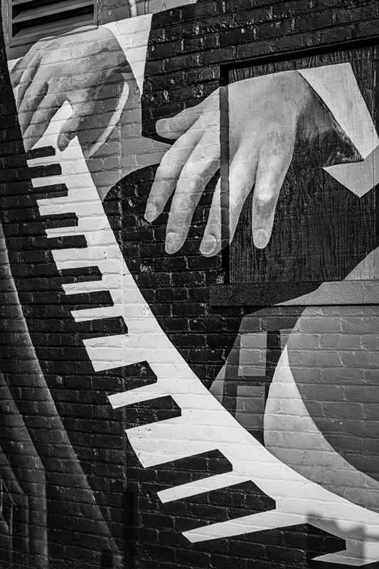 A close-up photo of a mural of hands playing a piano.