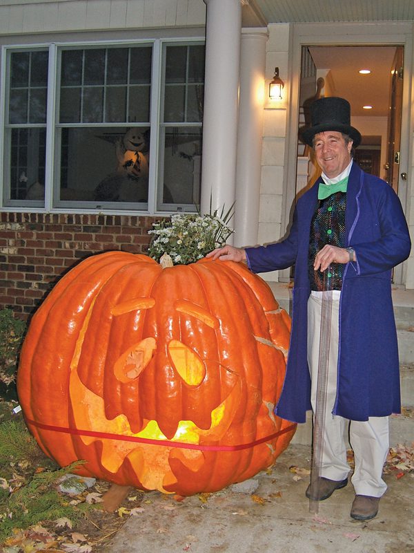 A man in costume next to a giant jack-o'-lantern