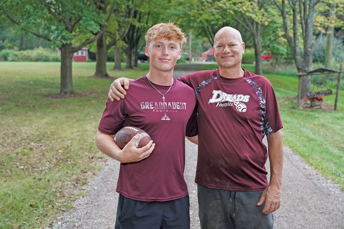 Nathan Gersh holding a football; his father Dan has his arm around Nathan's shoulders.