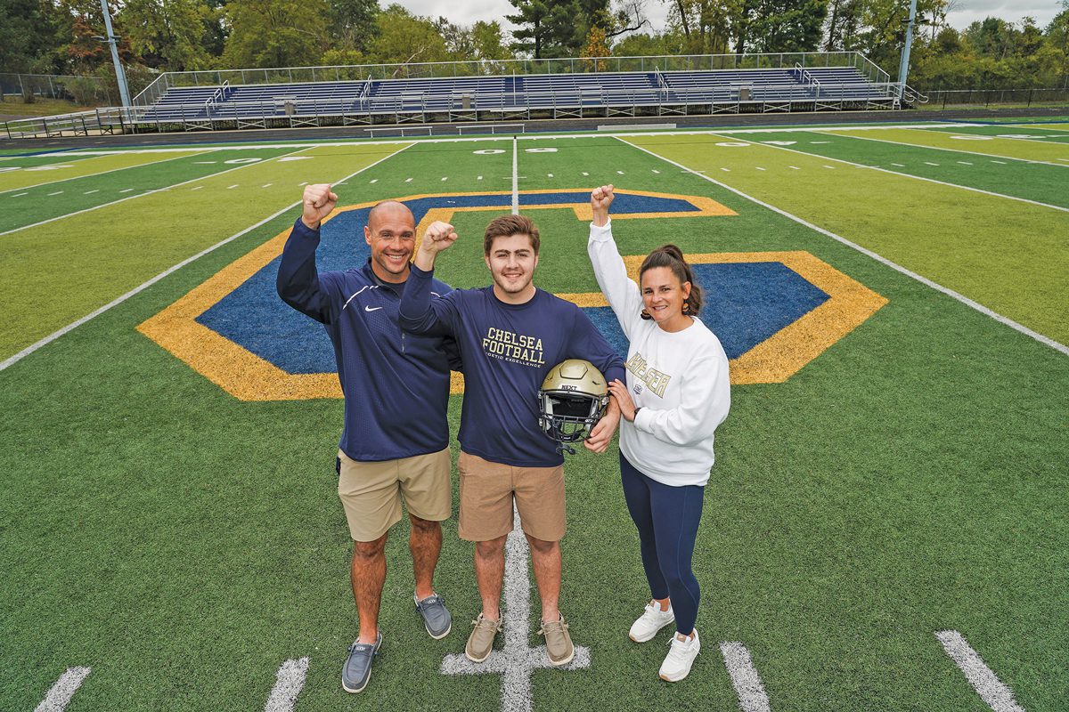 Joe, Tanner, and Jenni Linde standing on the Chelsea football field.