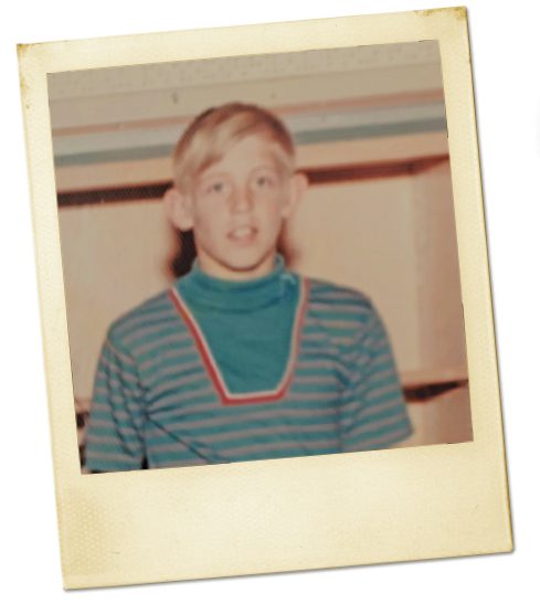 An old Polaroid photo of a boy with blonde hair and a blue sweater. 