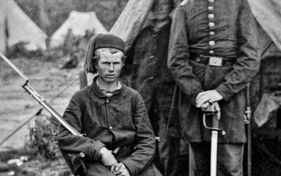 A very old photo of two Civil War soldiers, one sitting and one standing.