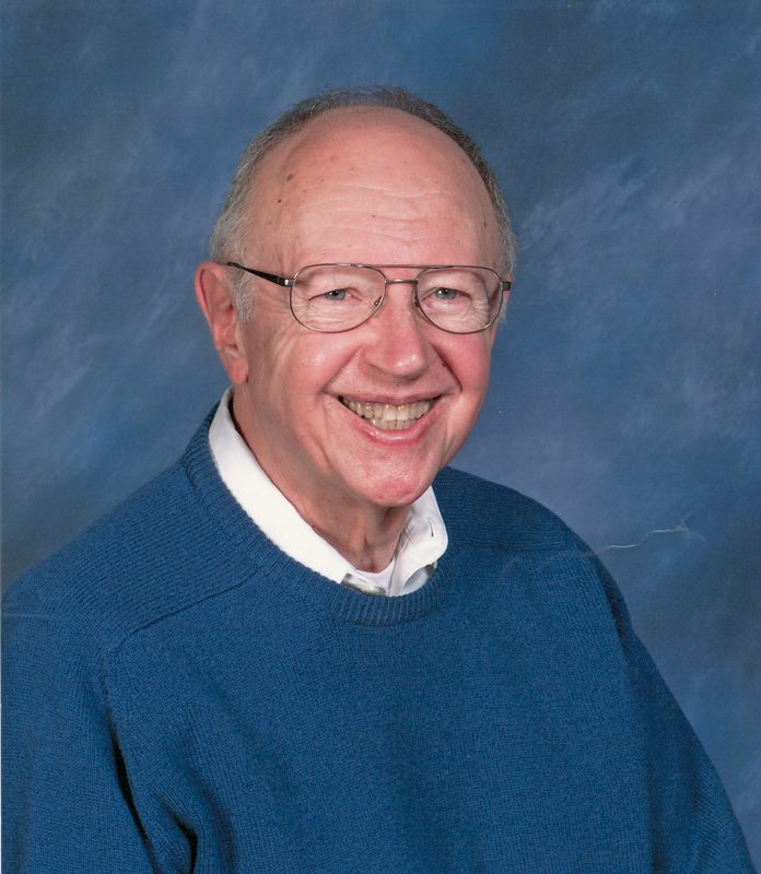 John Sampselle, an older man with glasses and a blue sweatshirt, smiling.