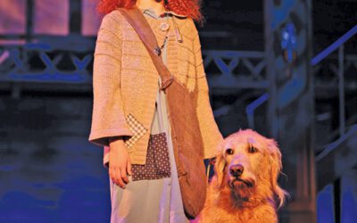 A child onstage singing next to a dog.