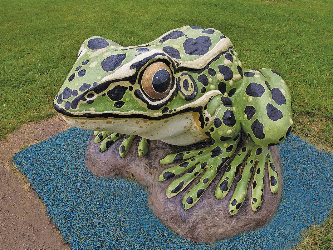A statue of a green spotted frog.