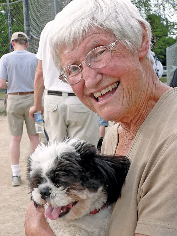 An elderly woman holding a small, fuzzy black-and-white dog