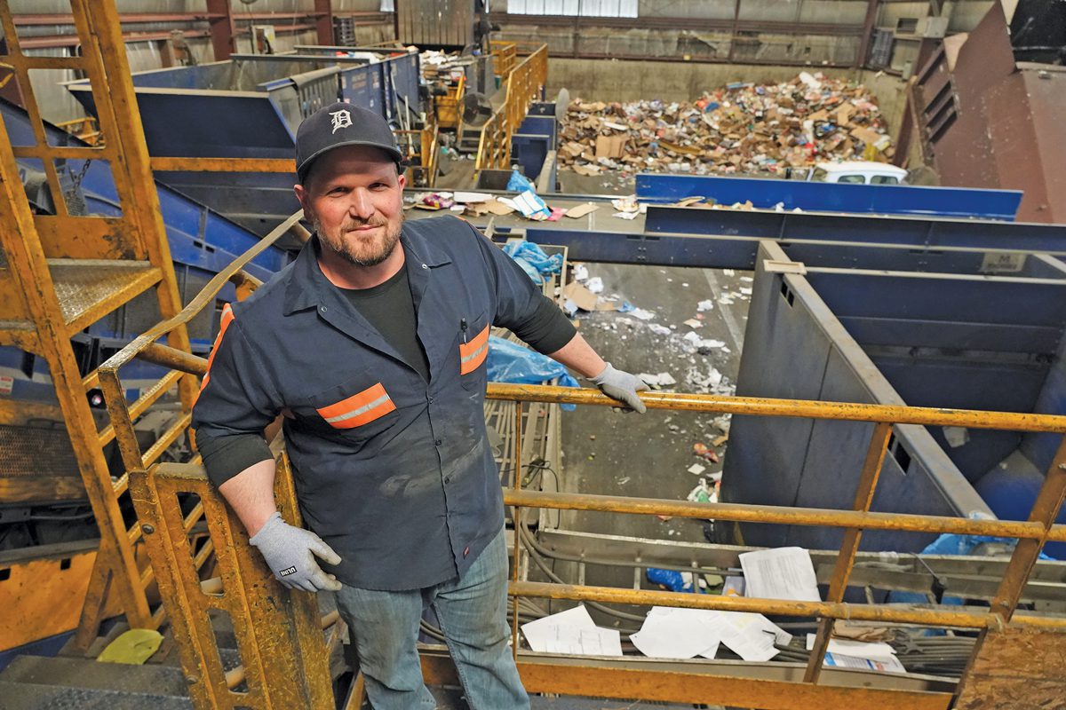 A man in work attire standing in a recycling center.