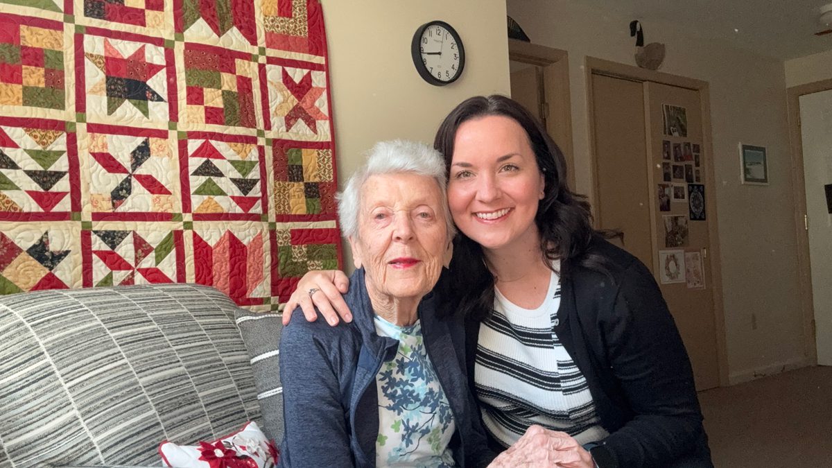 A young woman with her arm around an old woman.