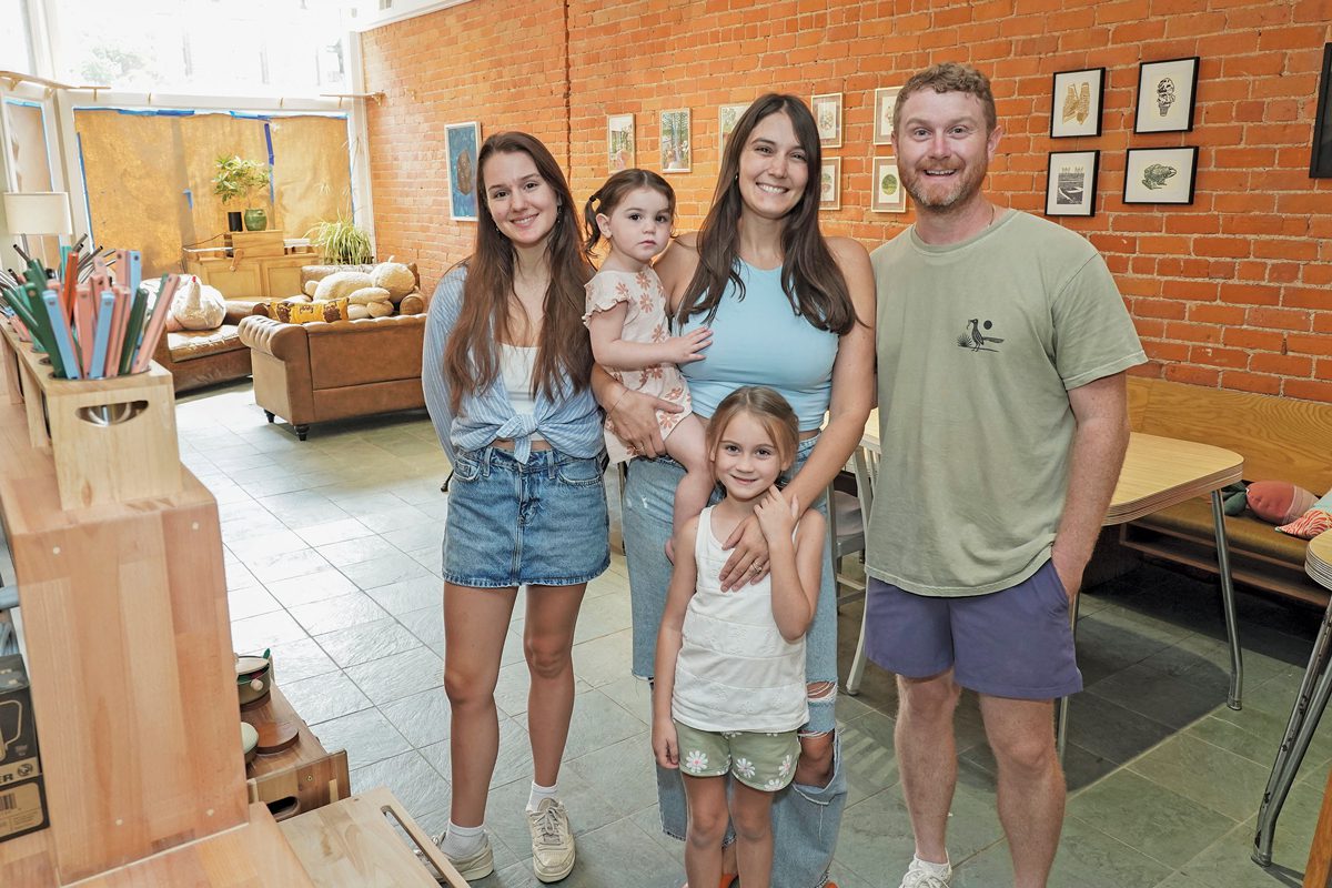 Three adults and two children pose in a colorful cafe