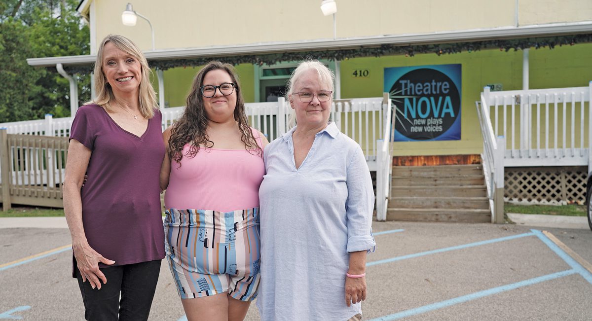 Three women stand in front of Theater NOVA.