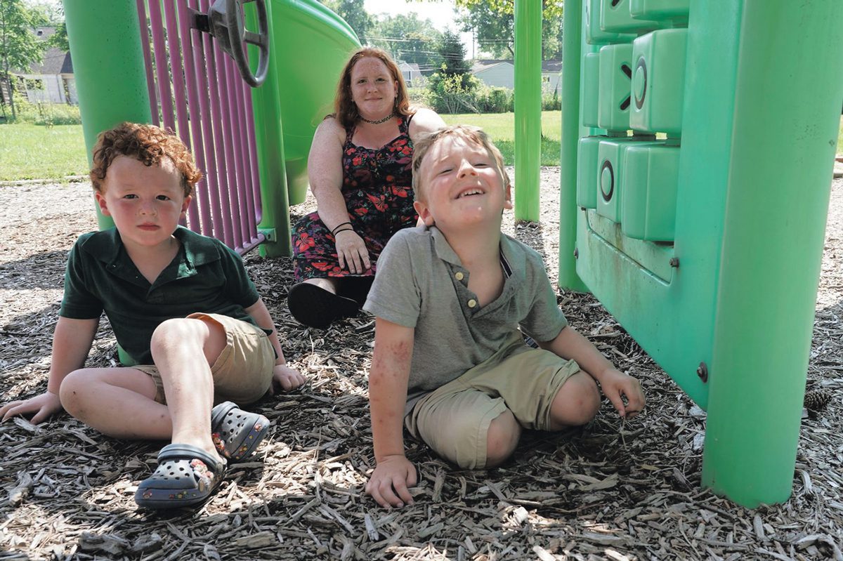 A woman and two children sit in a playground. 