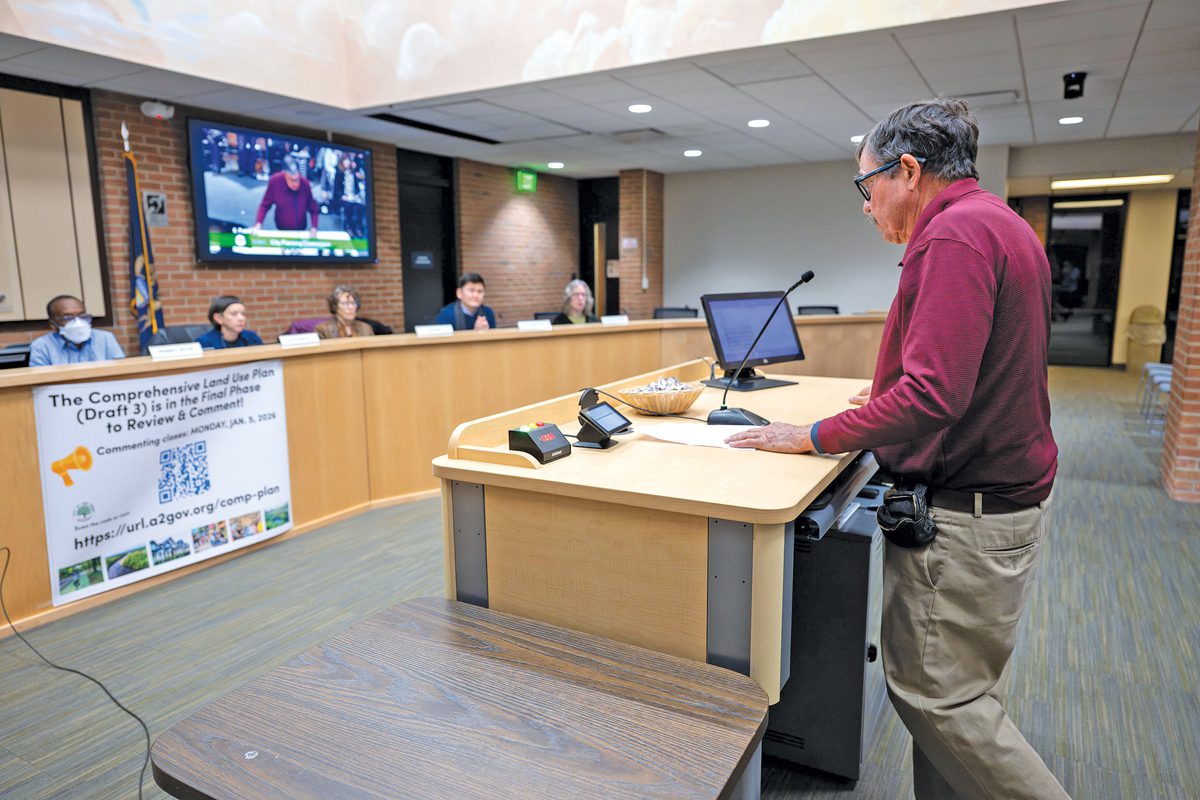 a man stands at a podium addressing the members of a planning commission