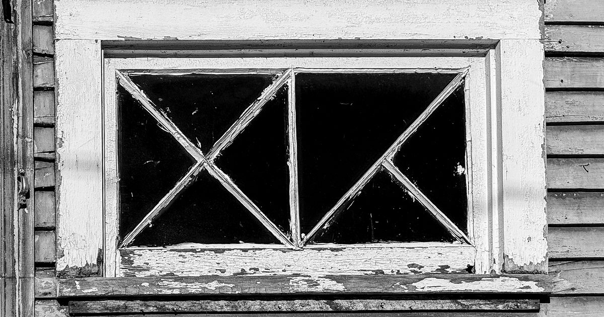 Black-and-white photo of a window surrounded by chipping paint