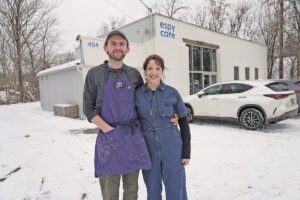 Peter Littlejohn and his wife Julia Knowles stand in front of a white building that says Espy Cafe