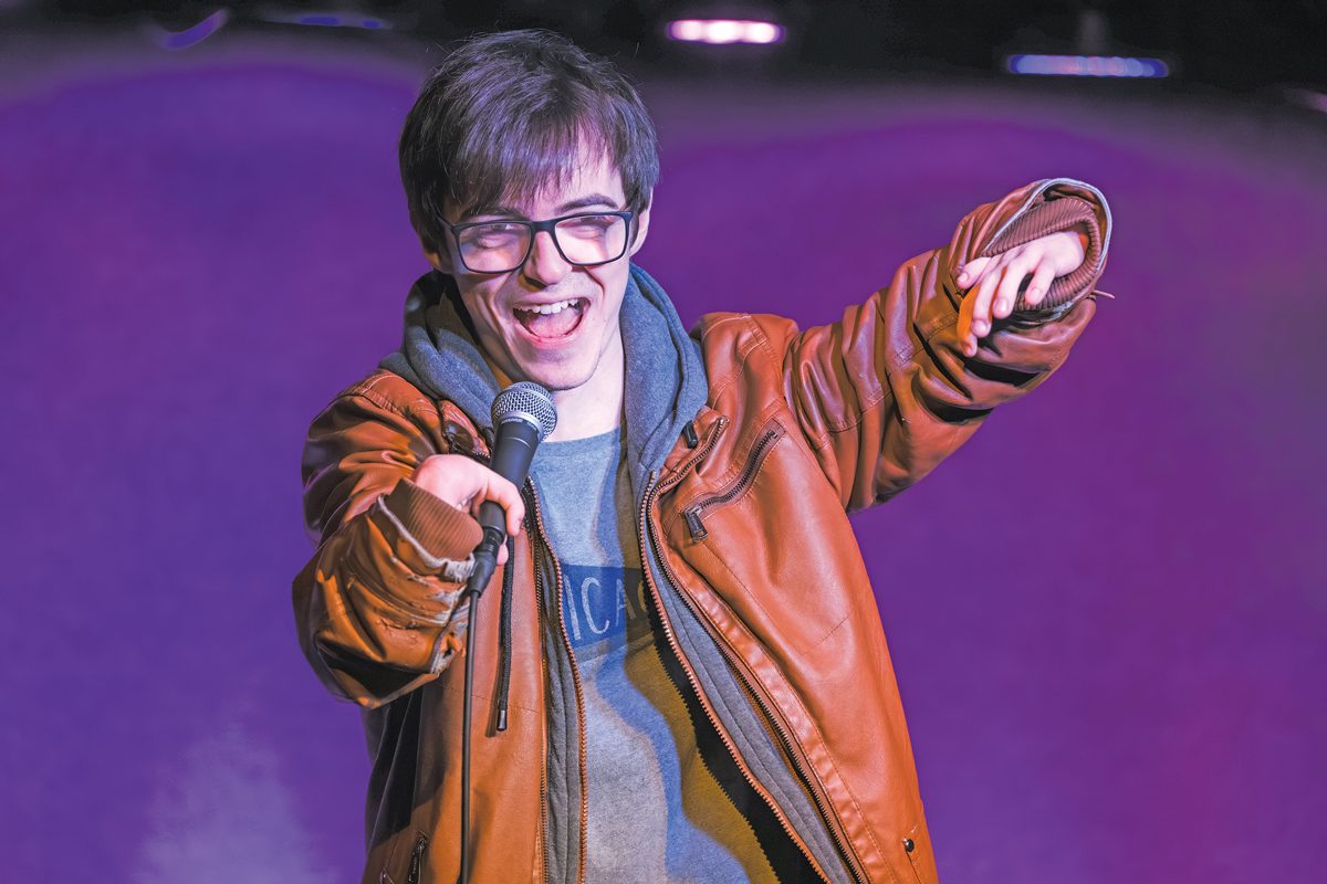 Jacob Barr holding a microphone and delivering a standup routine.