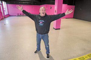 Ted Arnold stands in the new space for Pinball Pete's in front of a bright pink wall