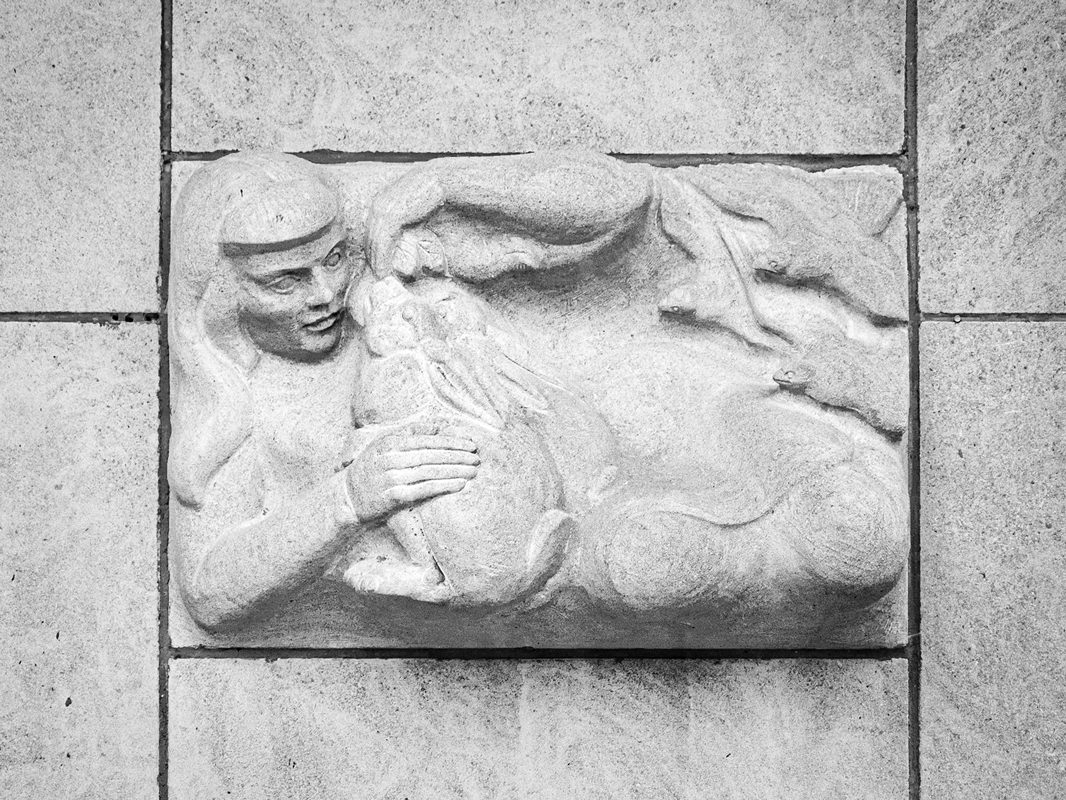 black and white photo of a carving in relief of a person holding a rabbit