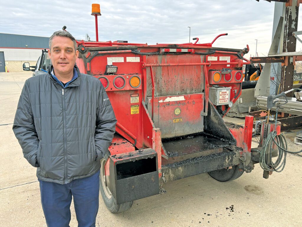 Paul Matthews standing in front of a piece of construction equipment.