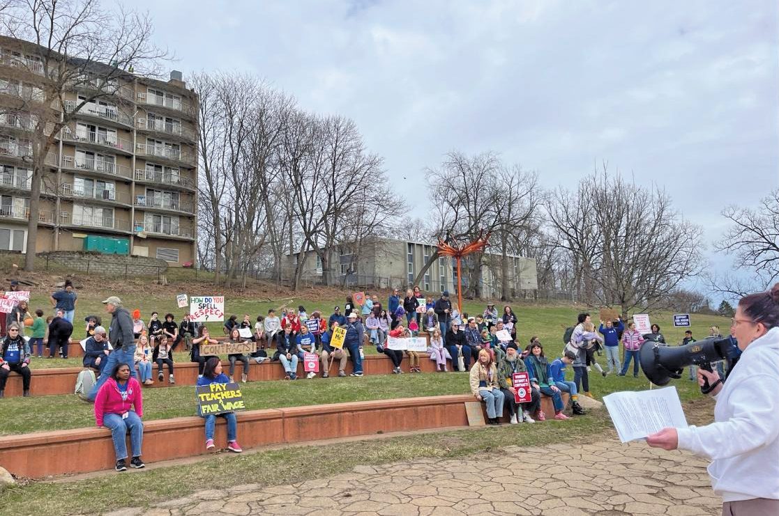 A group of people hold signs at a park
