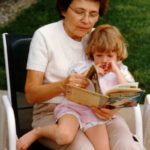 Margaret with a grandchild on her lap reading a book
