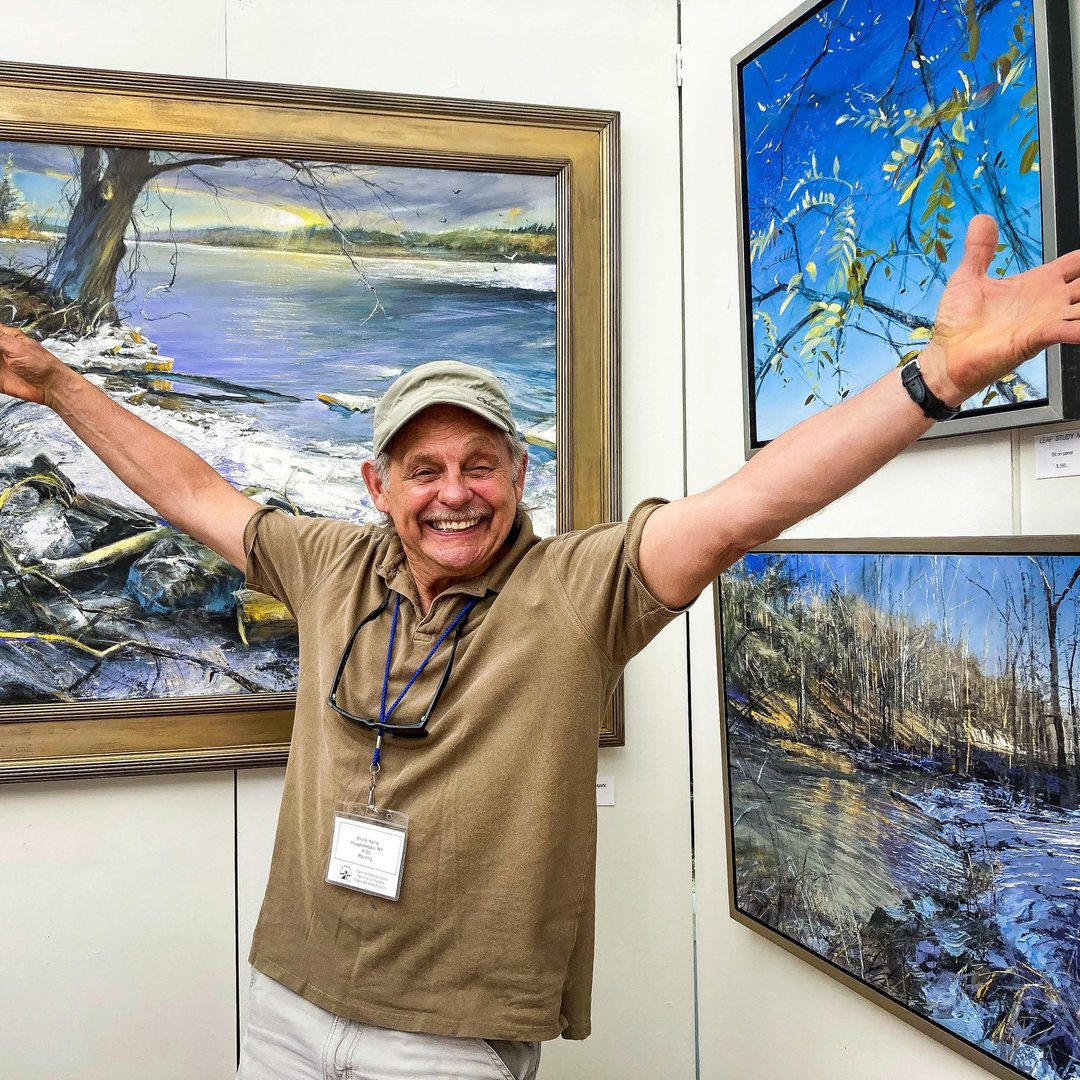 Phillip Harris stands in front of three of his paintings.