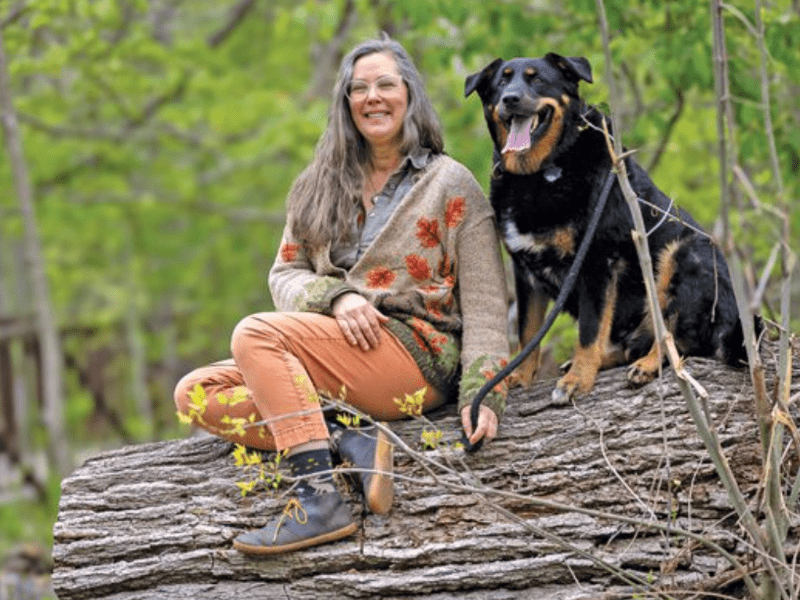 Woman on log with dog