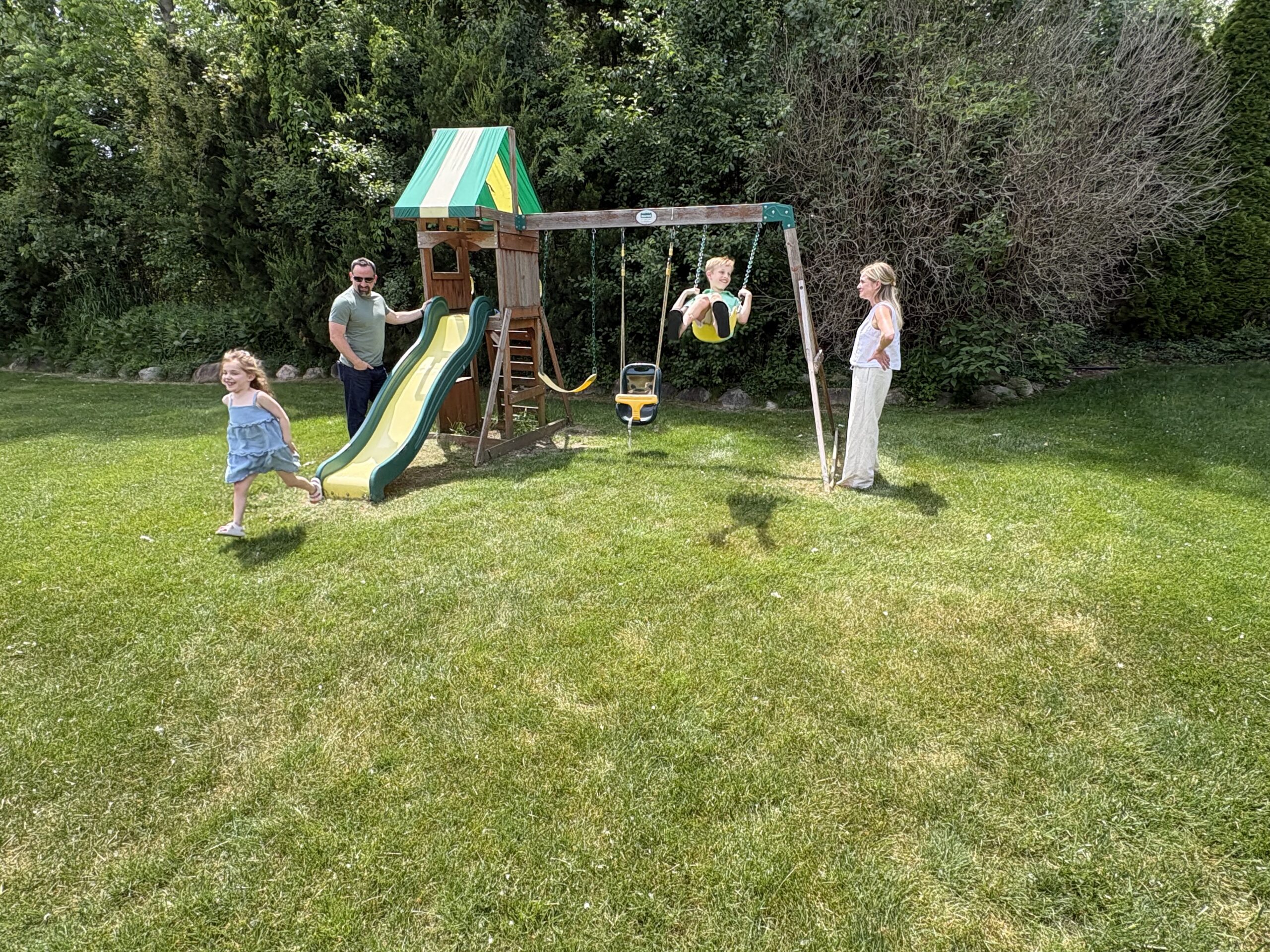 The Tenzillo family play on a swingset in their backyard.