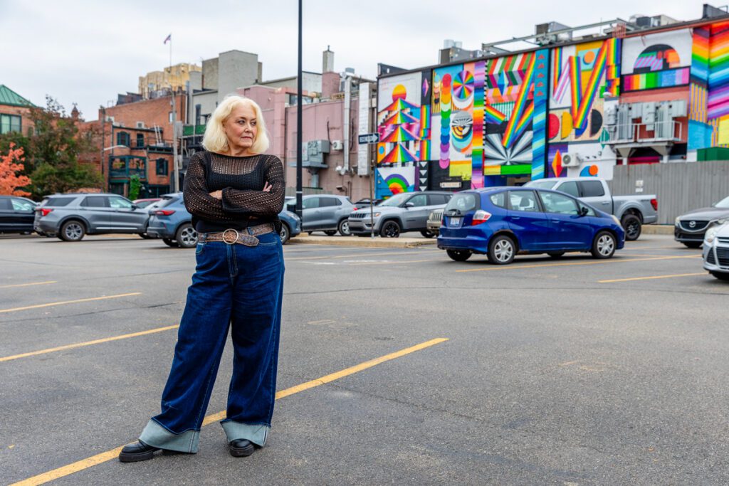 Kathleen London stands with arms crossed in the Kline's Lot with the mural on the Ark in the background.