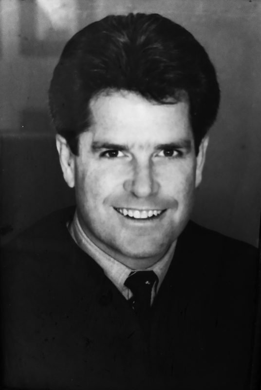 Black and white portrait of Timothy Connors smiling.